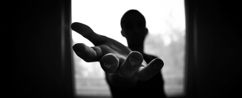 Silhouette of a person holding their hand out